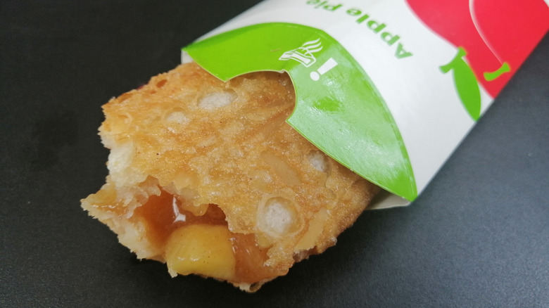 Half-eaten McDonald's apple pie sticking out of cardboard sleeve.
