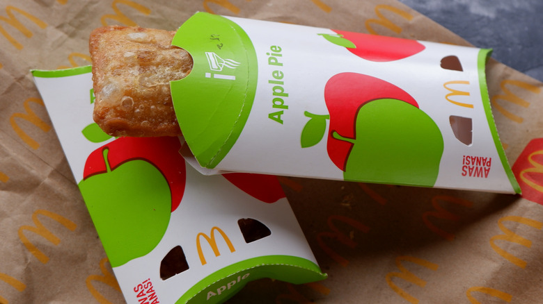 Two McDonald's apple pies in cardboard sleeves on top of paper bag.