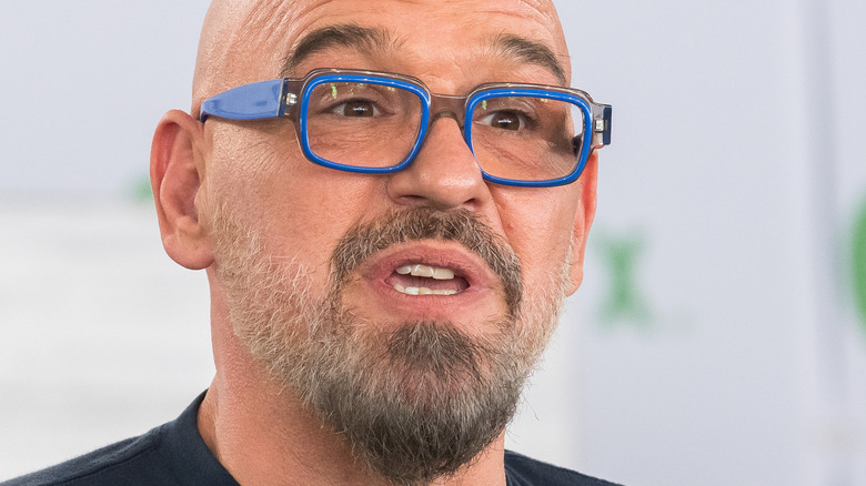 Michael Symon speaking while wearing blue glasses