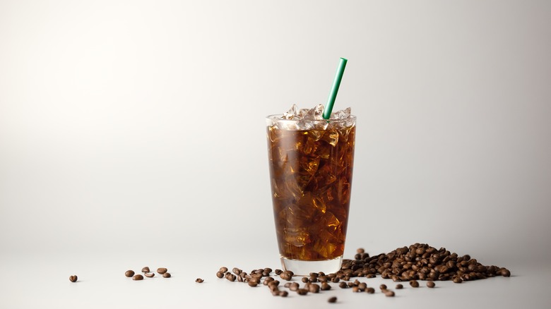 Iced coffee with straw and coffee beans