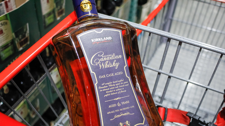 A bottle of Costco's Kirkland Signature Blended Canadian Whisky in a shopping cart