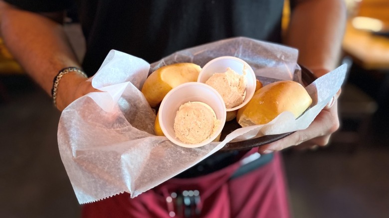Server holding basket of bread rolls at Texas Roadhouse