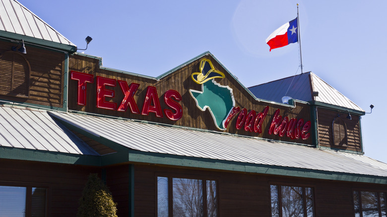 Texas Roadhouse storefront daytime with Texas flag flying