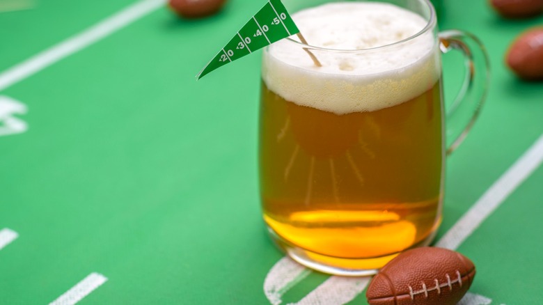 A mug of beer on a miniature football field with mini footballs
