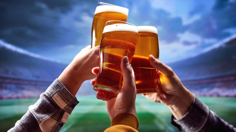 Raised glasses of beer at a football stadium