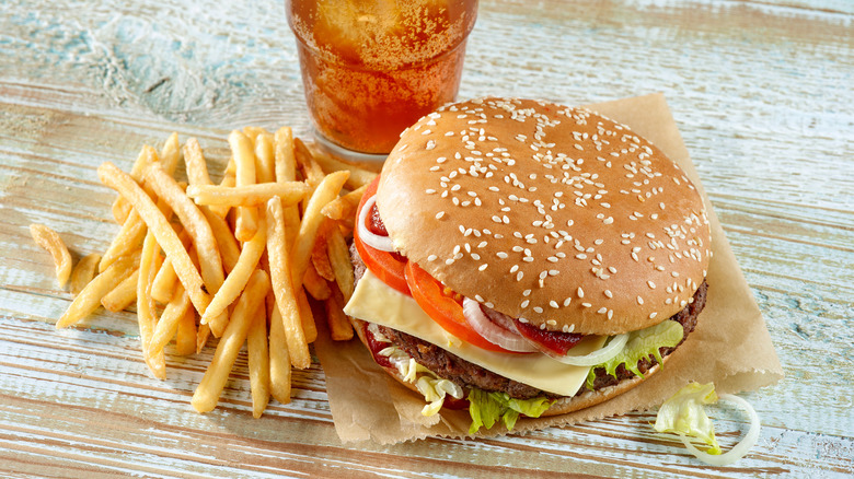 Fast food hamburger, french fries, and soda on table.