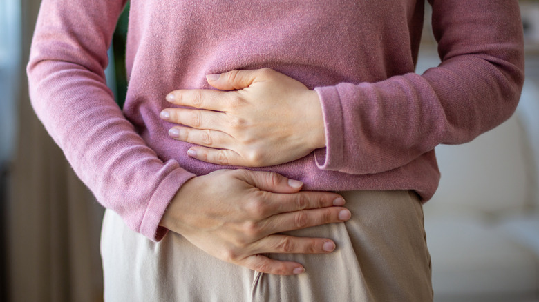 Person holding stomach due to pain and discomfort
