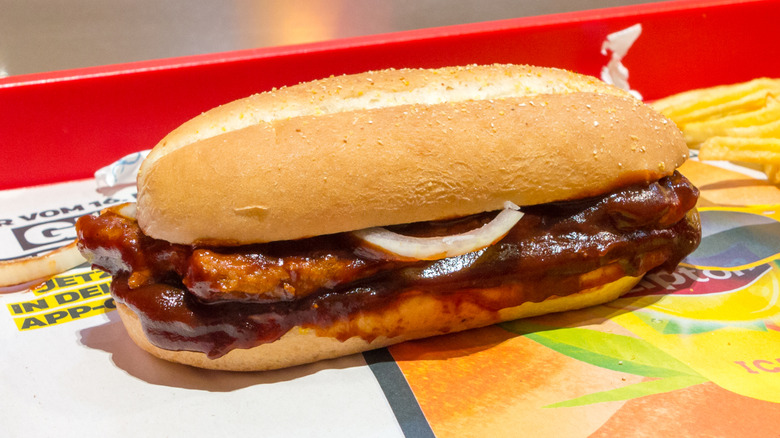 A McDonald's McRib sandwich on a tray inside a restaurant.
