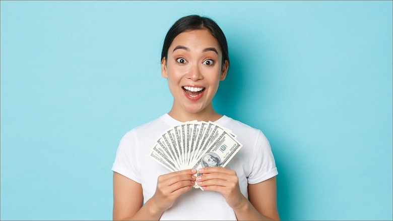 Woman smiling, holding money