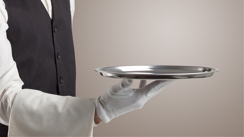 waiter wearing vest and gloves and serving food