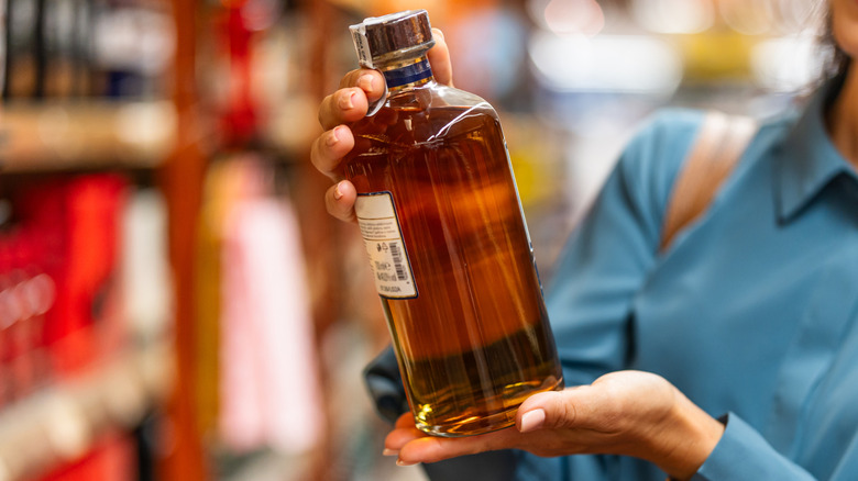 Person holding a bottle of bourbon inside a liquor store
