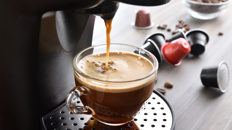 Coffeemaker dispensing coffee into glass mug.