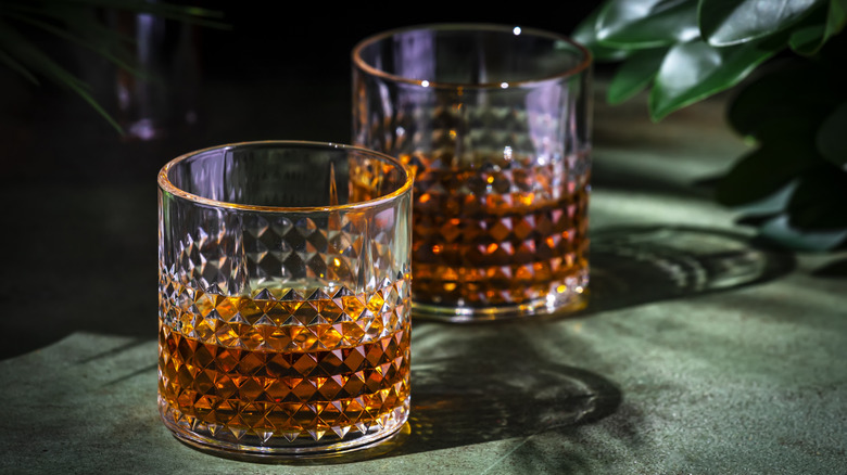 Two glasses of whiskey sitting on table.