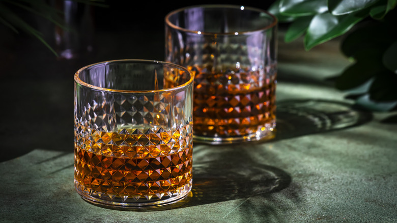 Two glasses of whiskey sitting on table.