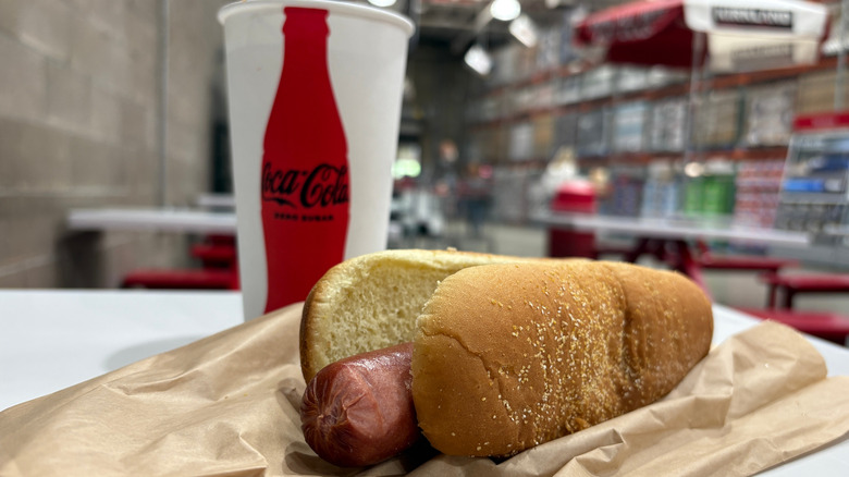 A hot dog and soft drink on a table inside a Costco warehouse store.