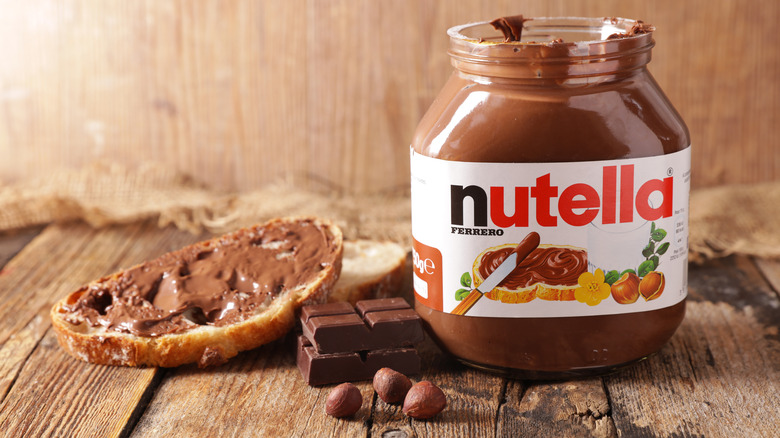 A jar of Nutella next to a slice of bread