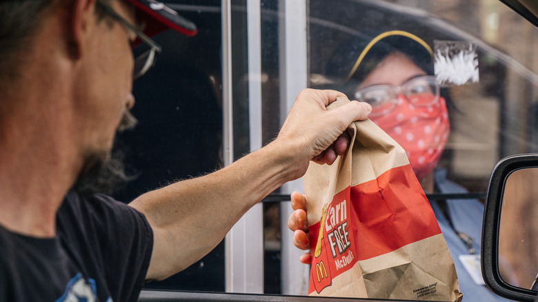 Drive-thru employee handing bag to driver