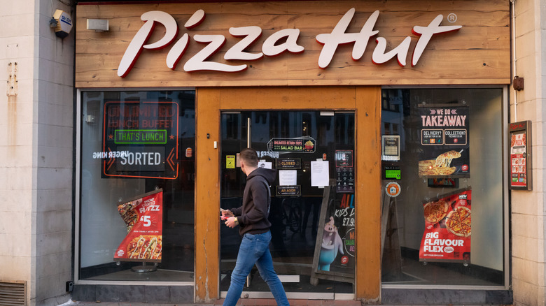 Person walking past a closed Pizza Hut location.
