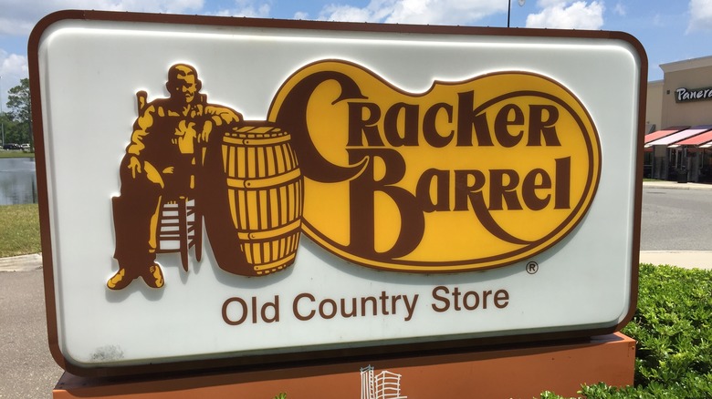 A sign for Cracker Barrel surrounded by greenery