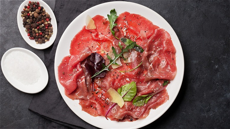 carpaccio on plate with salad greens and cheese