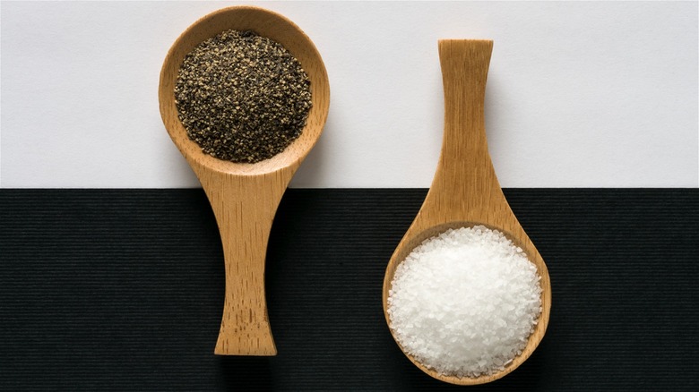 Freshly ground pepper and kosher salt in wooden spoons.