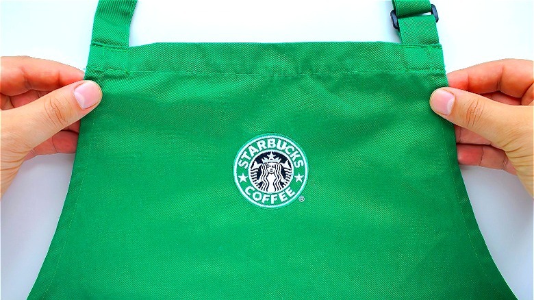 Hands holding green Starbucks apron