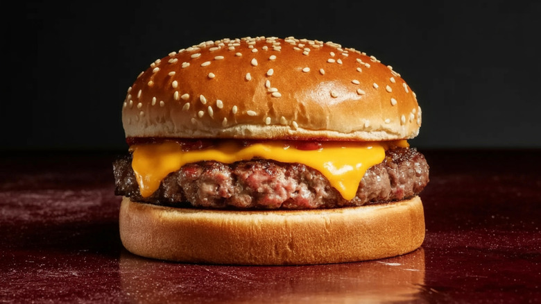 a classic cheeseburger with ketchup in a sesame seed bun on a wood table