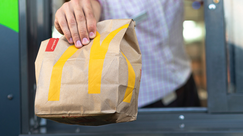 Drive-thru worker handing McDonald's bag to car