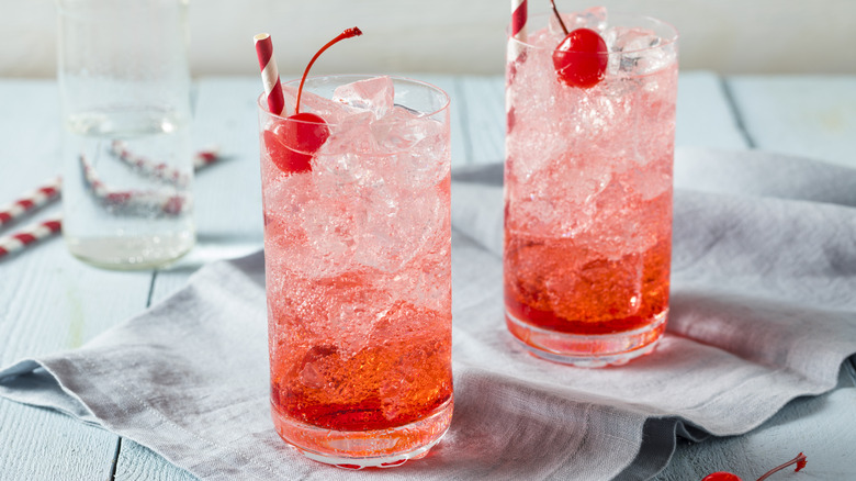 Two Shirley Temples with striped straws on grey cloth