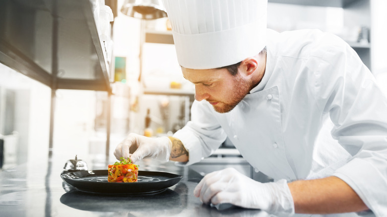 A chef at a fine dining restaurant crafting a dish