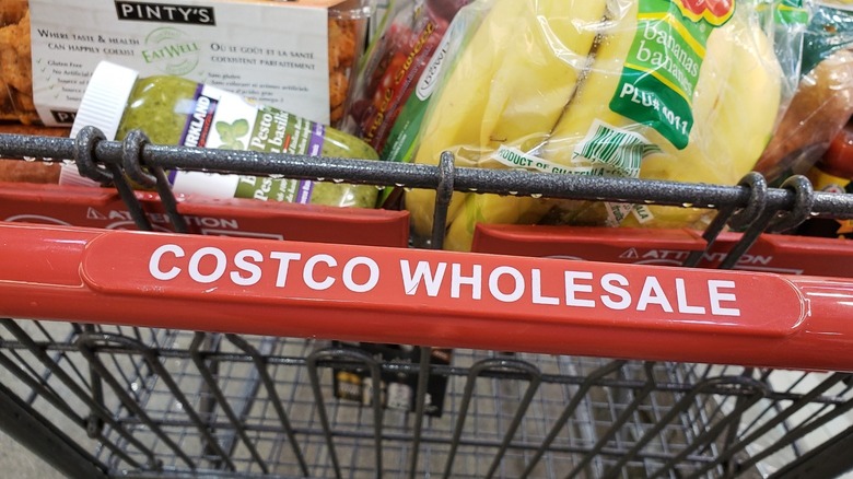 close up of costco cart, focusing on cart handle, jar of pesto, and bananas