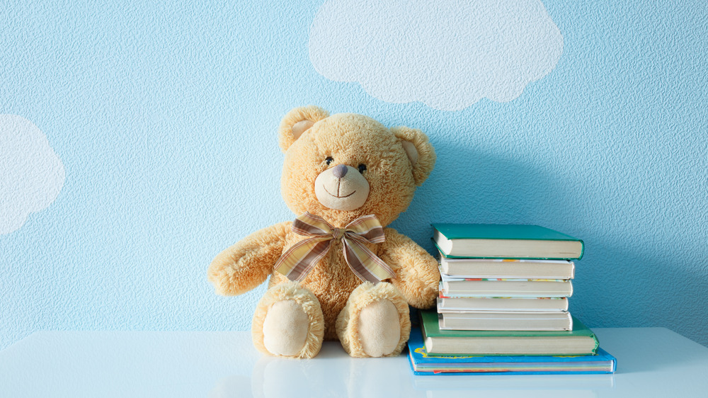 Teddy bear and book stack against cloud background