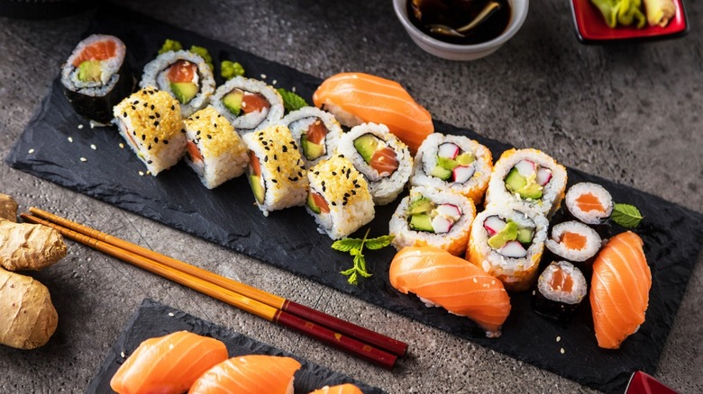 platter of assorted sushi with soy sauce and chop sticks on the side