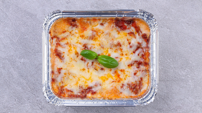 a woman taking a lasagna out of an oven