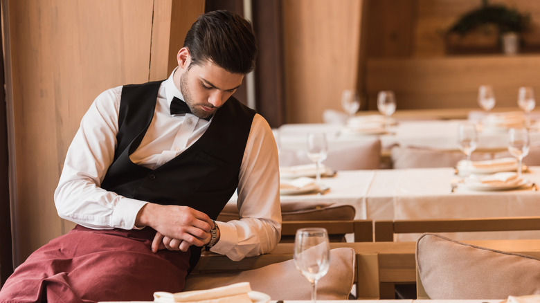 A waiter looking at his watch 