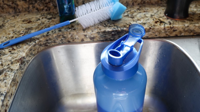 Plastic water bottle being cleaned in sink