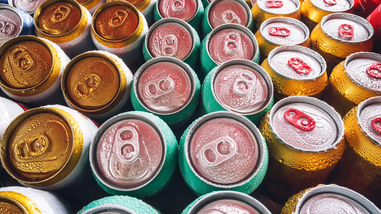 Rows of drink cans with condensation drops on them 