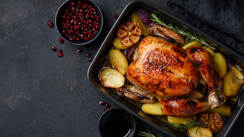 A turkey in a pan with potatoes and herbs
