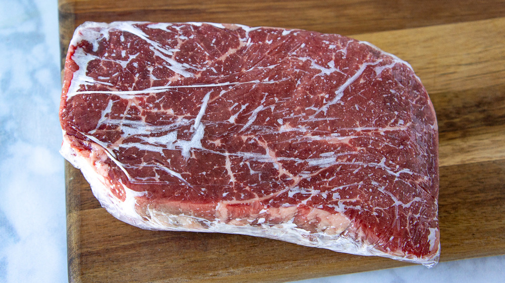 a frozen steak on a wooden cutting board