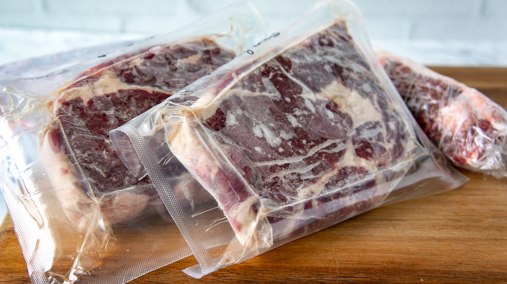 frozen steaks piled on a wooden cutting board