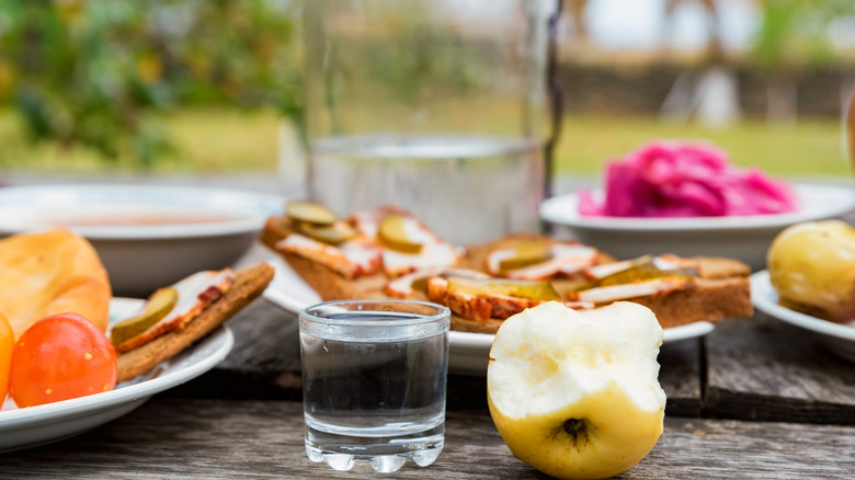 Appetizer foods and a glass of vodka on a table top