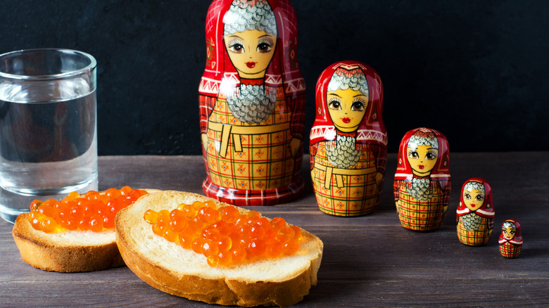 Russian dolls, caviar on toast, and glass of vodka on gray background