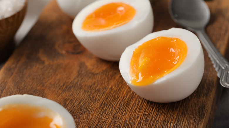 Perfectly soft-boiled eggs cut in half on a wooden platter