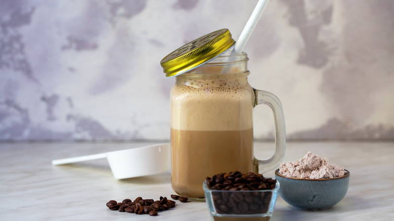 A mason jar filled with iced coffee with added protein powder.