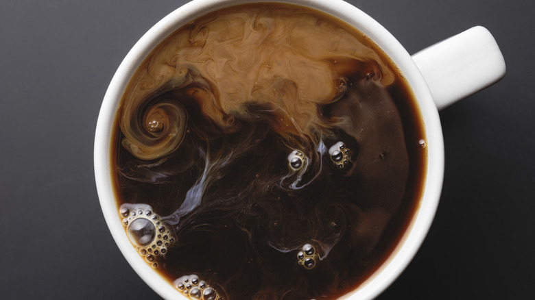 View from above of coffee swirling with cream.