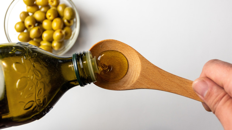 Pouring olive oil into wooden spoon