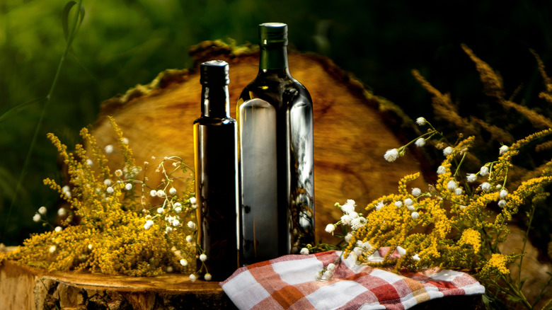 Dark glass olive oil bottle on a log