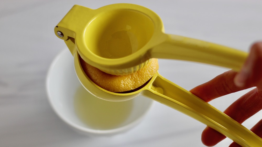 Squeezing lemon with yellow juicer