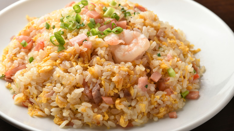 Shrimp fried rice with scallions and egg in white ceramic bowl.