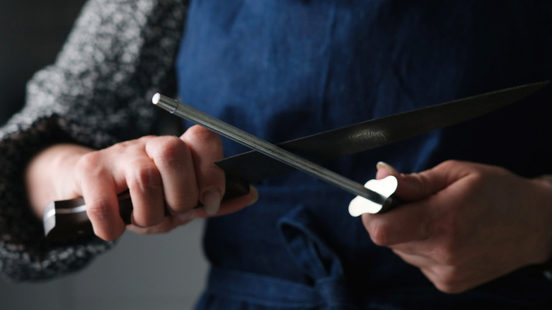 Person sharpening knife with honing rod